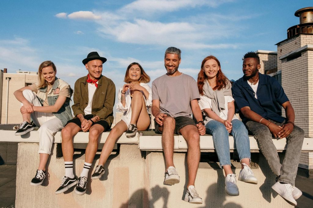 Diverse group of friends laughing and relaxing on a sunny rooftop.